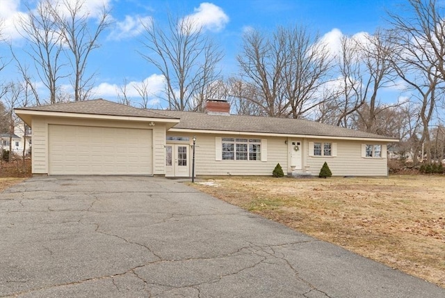 ranch-style home featuring aphalt driveway, a front lawn, a chimney, and an attached garage