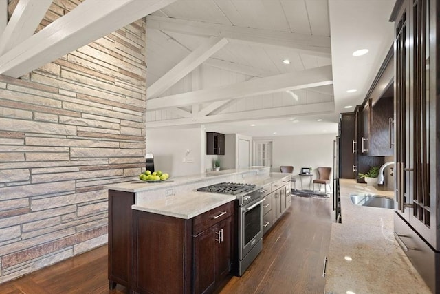 kitchen featuring a sink, high end stove, dark wood-style flooring, and vaulted ceiling with beams