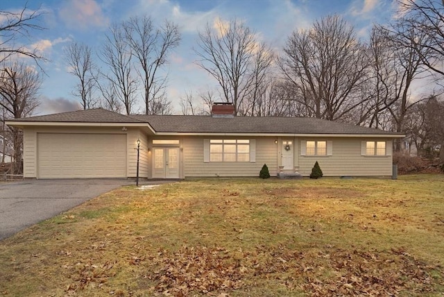 ranch-style home featuring aphalt driveway, french doors, a front lawn, and a garage