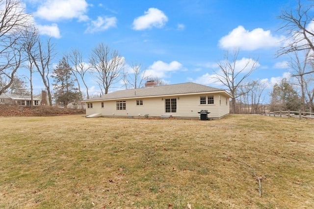 back of property with a yard, a chimney, and fence