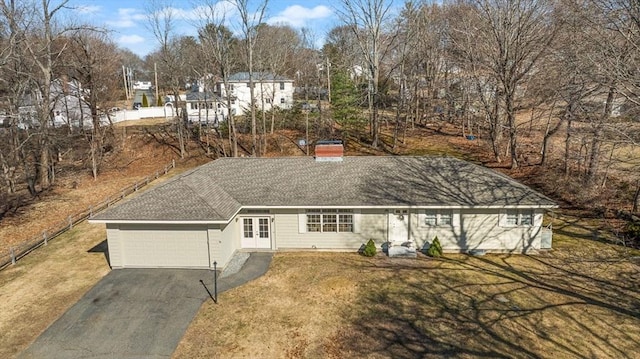 view of front of house featuring a front lawn, aphalt driveway, french doors, an attached garage, and a chimney