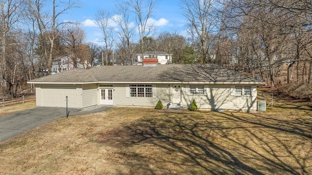 ranch-style home featuring fence, aphalt driveway, a front yard, central AC unit, and an attached garage