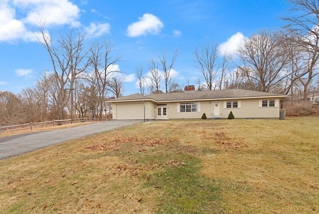 ranch-style house featuring fence, a front yard, a chimney, a garage, and driveway