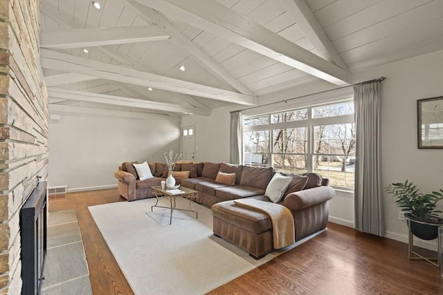 living room featuring visible vents, baseboards, lofted ceiling with beams, a fireplace, and wood finished floors