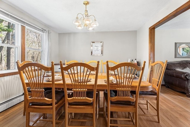dining area featuring a chandelier, baseboard heating, and light wood-style flooring