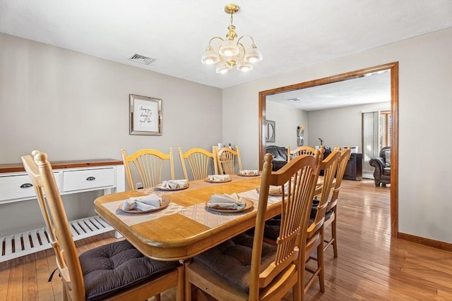dining area with light wood finished floors, a chandelier, and baseboards