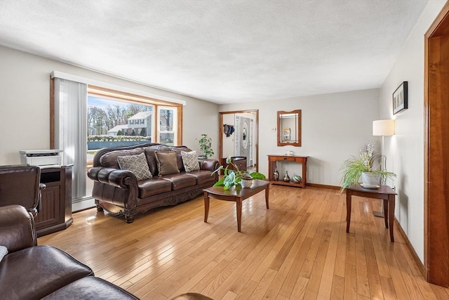 living room featuring a baseboard radiator, light wood-style flooring, and baseboards