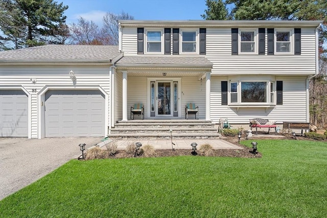 view of front of home featuring a porch, driveway, a front lawn, and a garage