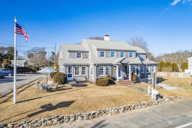 shingle-style home featuring a shingled roof and fence