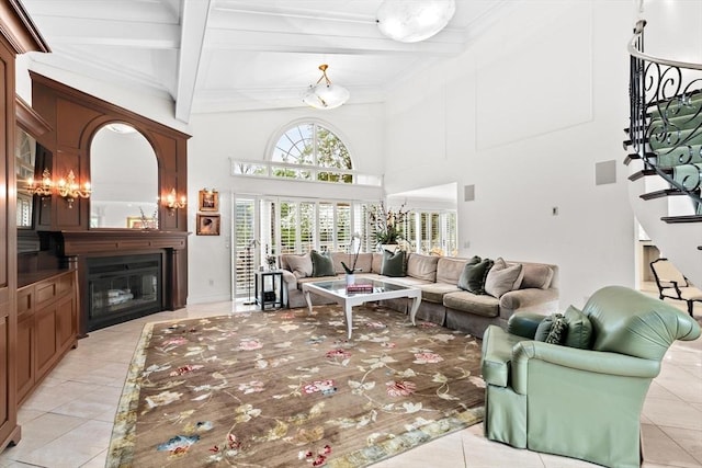 living room featuring light tile patterned flooring, stairway, a glass covered fireplace, beam ceiling, and a towering ceiling