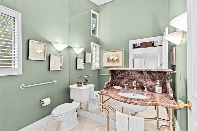 half bath featuring toilet, baseboards, a high ceiling, and a sink