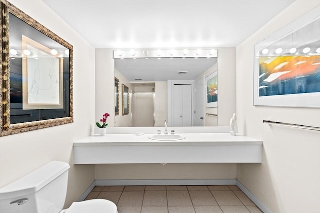 bathroom featuring baseboards, tile patterned flooring, toilet, and vanity
