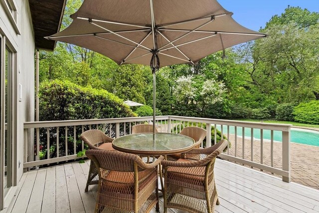 wooden terrace with outdoor dining space and an outdoor pool
