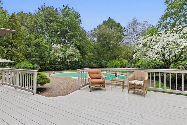 wooden deck featuring an outdoor pool and view of wooded area