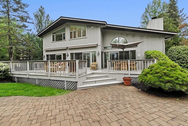 rear view of property featuring a chimney and a deck