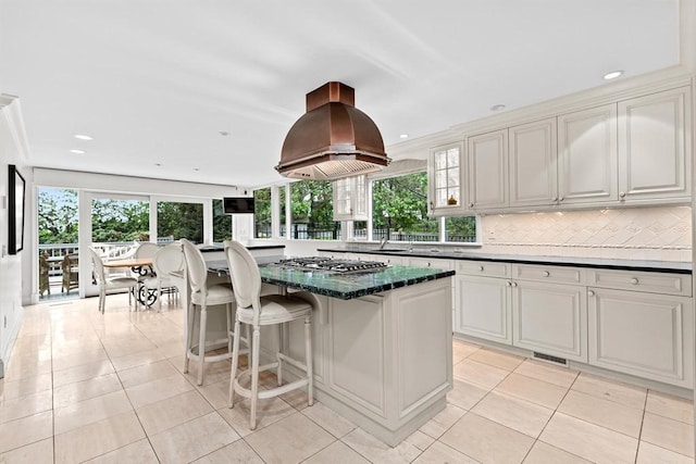 kitchen with exhaust hood, light tile patterned floors, plenty of natural light, a center island, and recessed lighting
