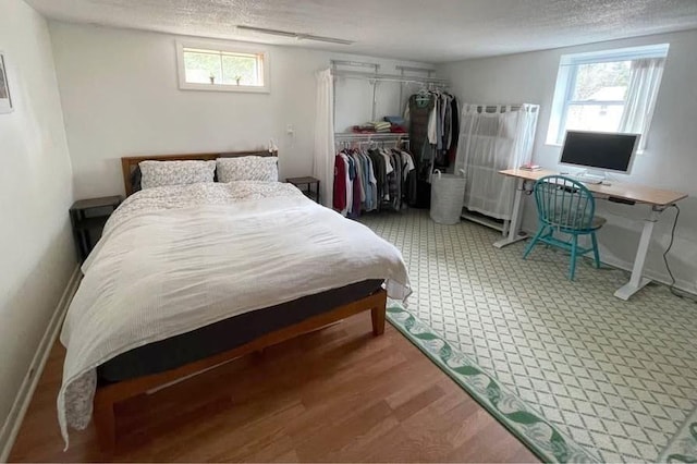 120 Tracy Cir, Amherst, MA 01002 - bedroom featuring multiple windows, a closet, a textured ceiling, wood finished floors, and baseboards
