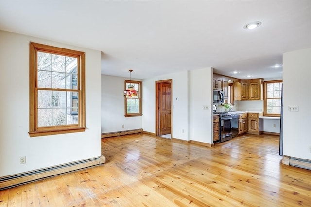 kitchen with baseboard heating, hanging light fixtures, light hardwood / wood-style floors, and gas range