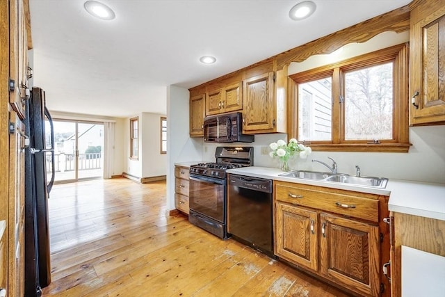 kitchen featuring sink, black appliances, and light hardwood / wood-style flooring