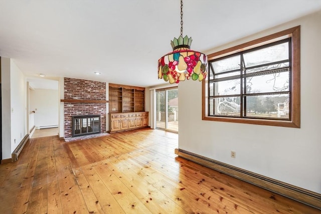 unfurnished living room featuring built in features, a baseboard radiator, light hardwood / wood-style floors, and a fireplace