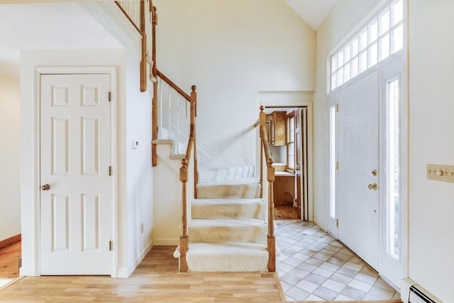 entryway featuring vaulted ceiling, light hardwood / wood-style flooring, and a baseboard heating unit