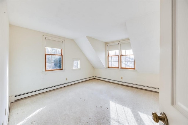 additional living space featuring a baseboard radiator, light carpet, and vaulted ceiling