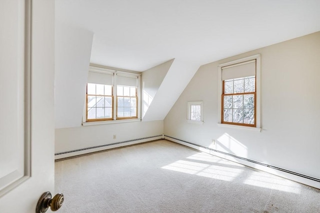 bonus room featuring vaulted ceiling, a healthy amount of sunlight, a baseboard radiator, and light carpet