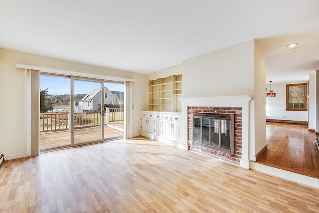 unfurnished living room featuring a fireplace, light wood-type flooring, and built in shelves