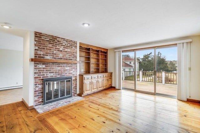 unfurnished living room with baseboard heating, a brick fireplace, and light hardwood / wood-style floors