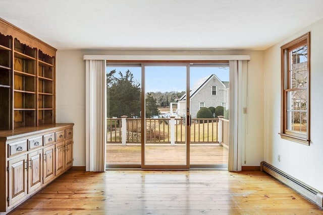 doorway to outside featuring light wood-type flooring, a healthy amount of sunlight, and a baseboard radiator