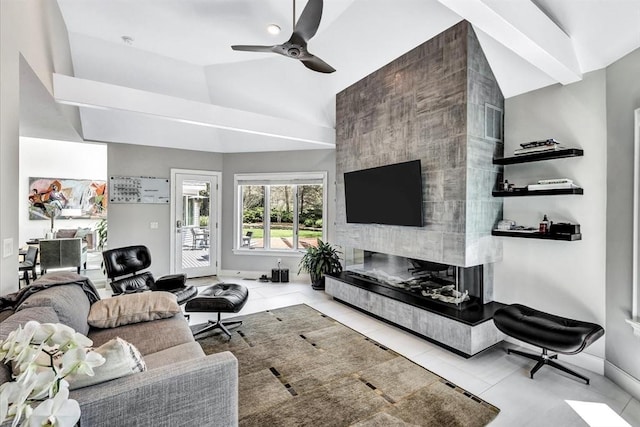 tiled living area featuring visible vents, ceiling fan, baseboards, a tiled fireplace, and lofted ceiling