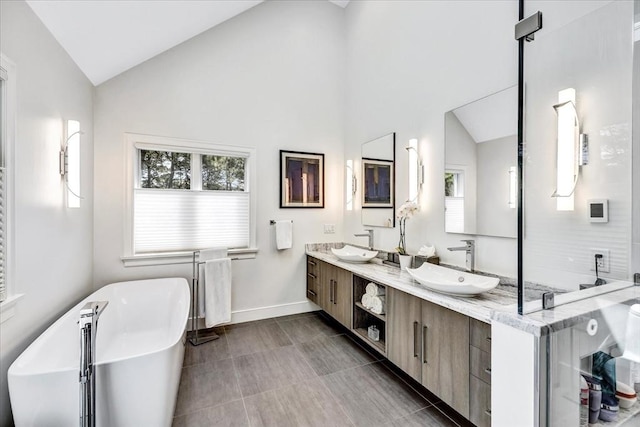 full bathroom featuring a sink, a freestanding tub, lofted ceiling, and double vanity