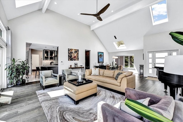 living area featuring beam ceiling, a skylight, wood finished floors, and high vaulted ceiling