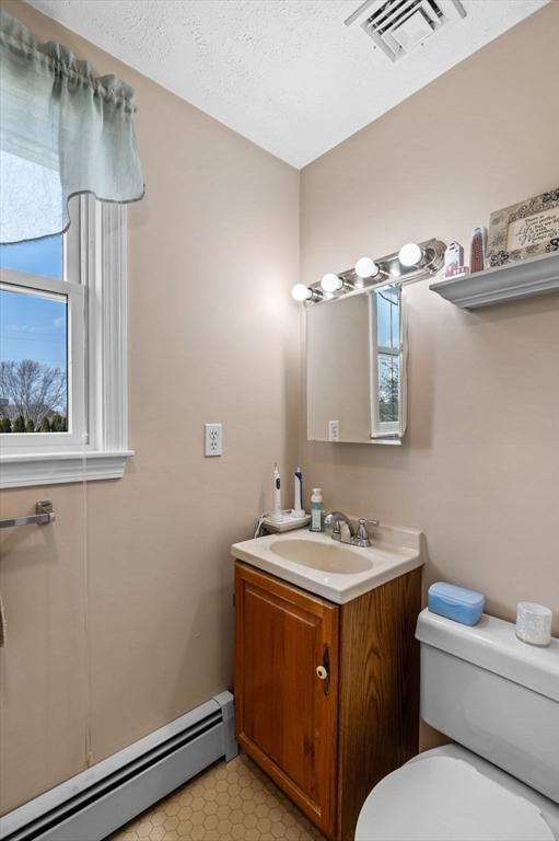 12 Jacobs Ave, Danvers, MA 01923 - bathroom with a baseboard heating unit, toilet, vanity, and a textured ceiling