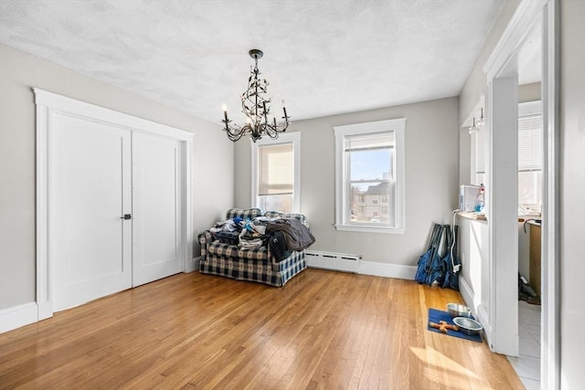 interior space with a textured ceiling, wood-type flooring, a baseboard radiator, and an inviting chandelier