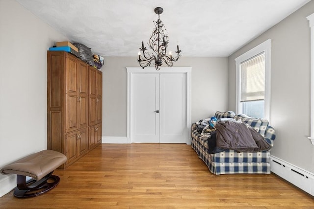 sitting room featuring baseboard heating, a chandelier, and light wood-type flooring