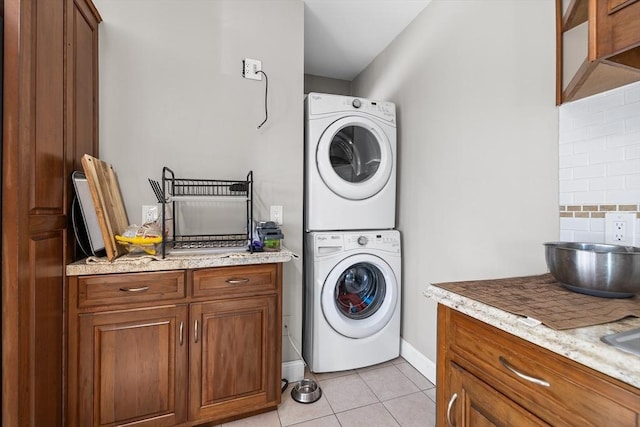 washroom featuring light tile patterned floors and stacked washer and dryer