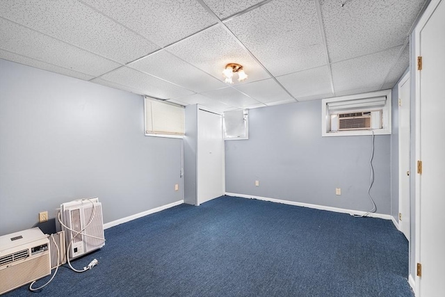 basement with dark carpet, a drop ceiling, and an AC wall unit