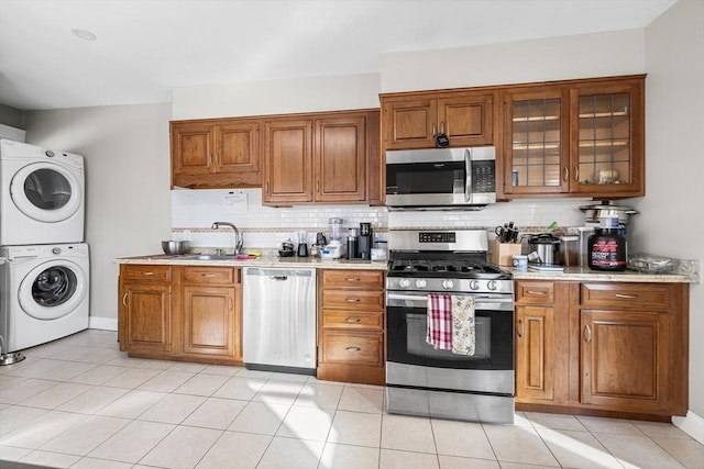 kitchen featuring backsplash, sink, stacked washer / dryer, and appliances with stainless steel finishes