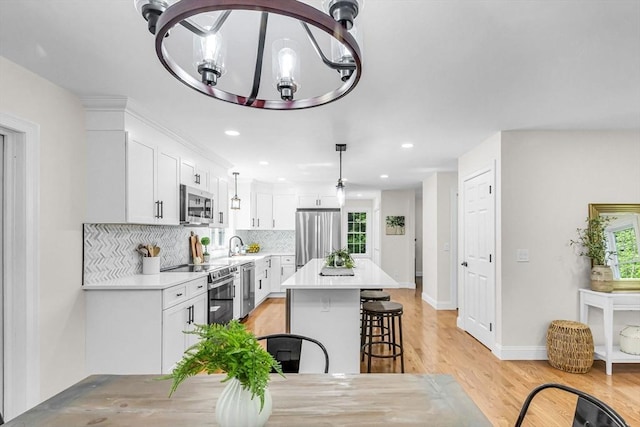 105 Forest Ave, Warren, MA 01585 - kitchen with stainless steel appliances, a kitchen bar, white cabinets, backsplash, and a kitchen island