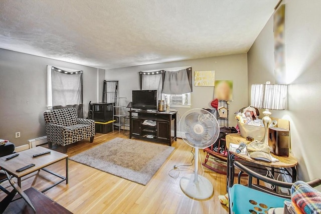 living room with a textured ceiling, light hardwood / wood-style floors, and baseboard heating