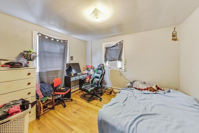 bedroom with baseboard heating and light hardwood / wood-style flooring