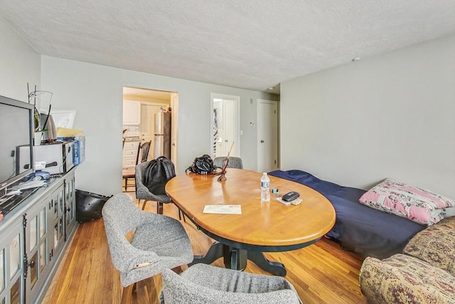 dining space with a textured ceiling and light hardwood / wood-style floors