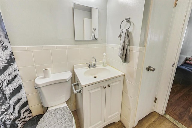 bathroom featuring vanity, tile walls, and toilet