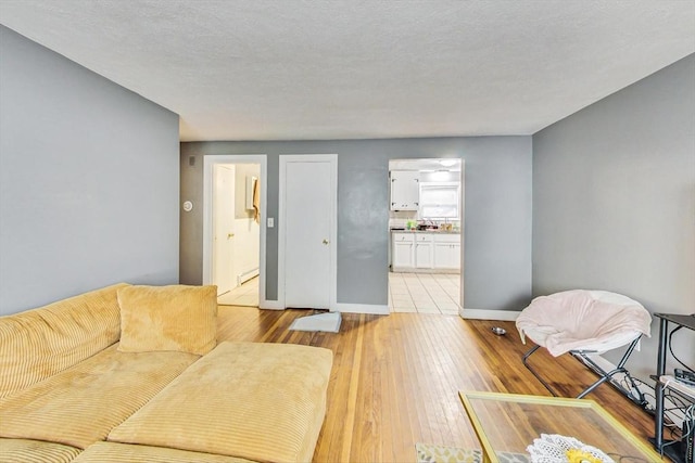 living room with light hardwood / wood-style floors, a textured ceiling, and a baseboard heating unit