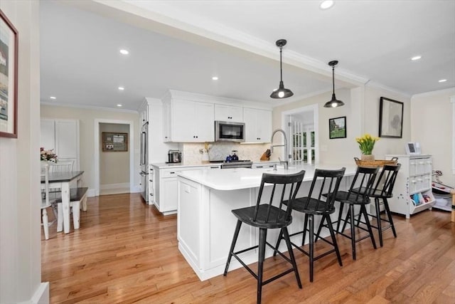 22 High St, Hingham, MA 02043 - kitchen featuring stainless steel appliances, ornamental molding, decorative backsplash, a sink, and a breakfast bar