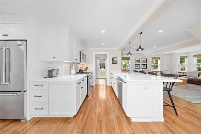 22 High St, Hingham, MA 02043 - kitchen with premium appliances, open floor plan, a kitchen bar, light wood-style floors, and crown molding
