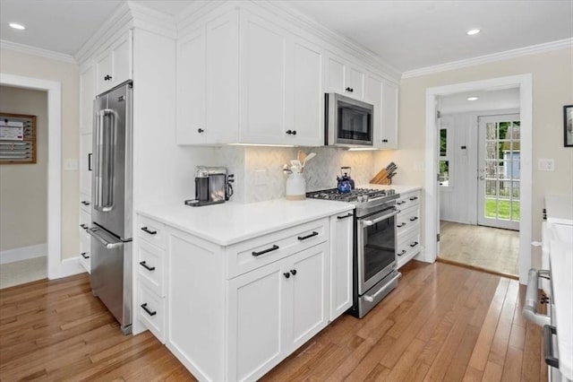 22 High St, Hingham, MA 02043 - kitchen featuring stainless steel appliances, light wood-style flooring, light countertops, white cabinetry, and crown molding