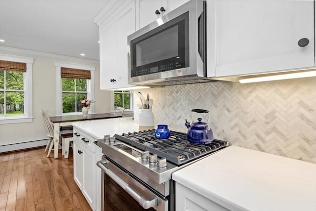 22 High St, Hingham, MA 02043 - kitchen with appliances with stainless steel finishes, a baseboard heating unit, decorative backsplash, white cabinets, and light countertops