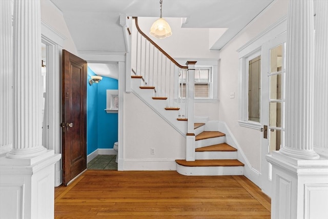 stairs featuring ornate columns and hardwood / wood-style floors